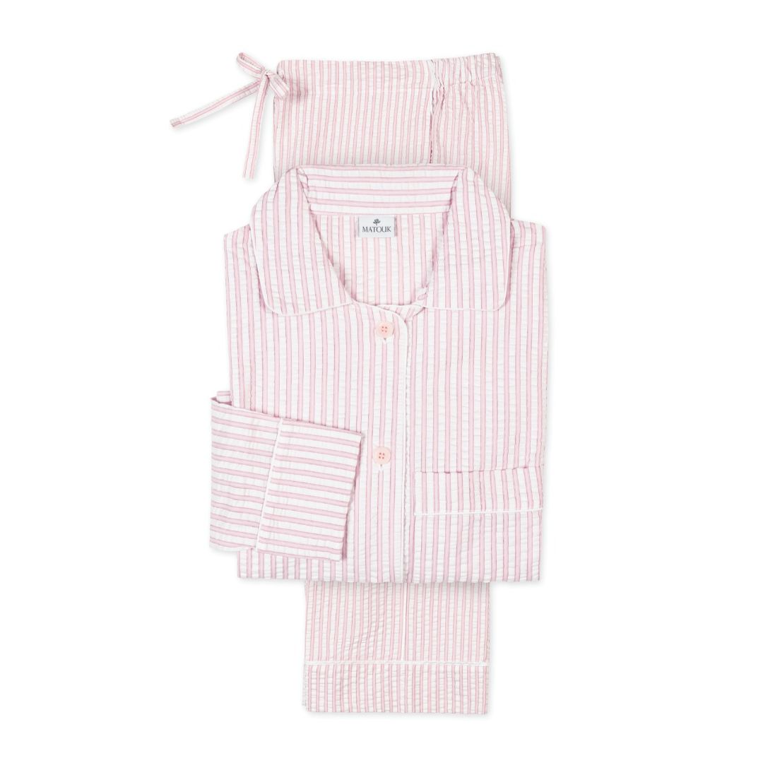 Pink and white striped loungewear set with long sleeves, seersucker cotton pajamas folded neatly with a drawstring waist.