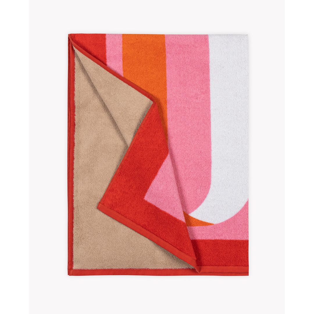matouk ribbon beach towel in flamingo folded with the reverse tan color showing