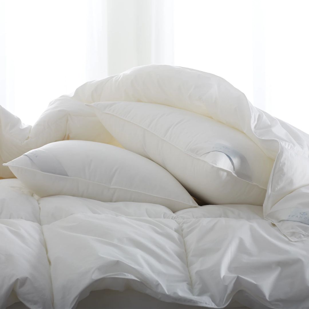 White comforter and pillows on a bed with a light background