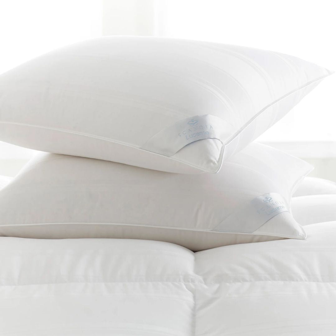 Two Scandia Home pillows stacked on a white bed, filled with hypoallergenic Hungarian white goose down.