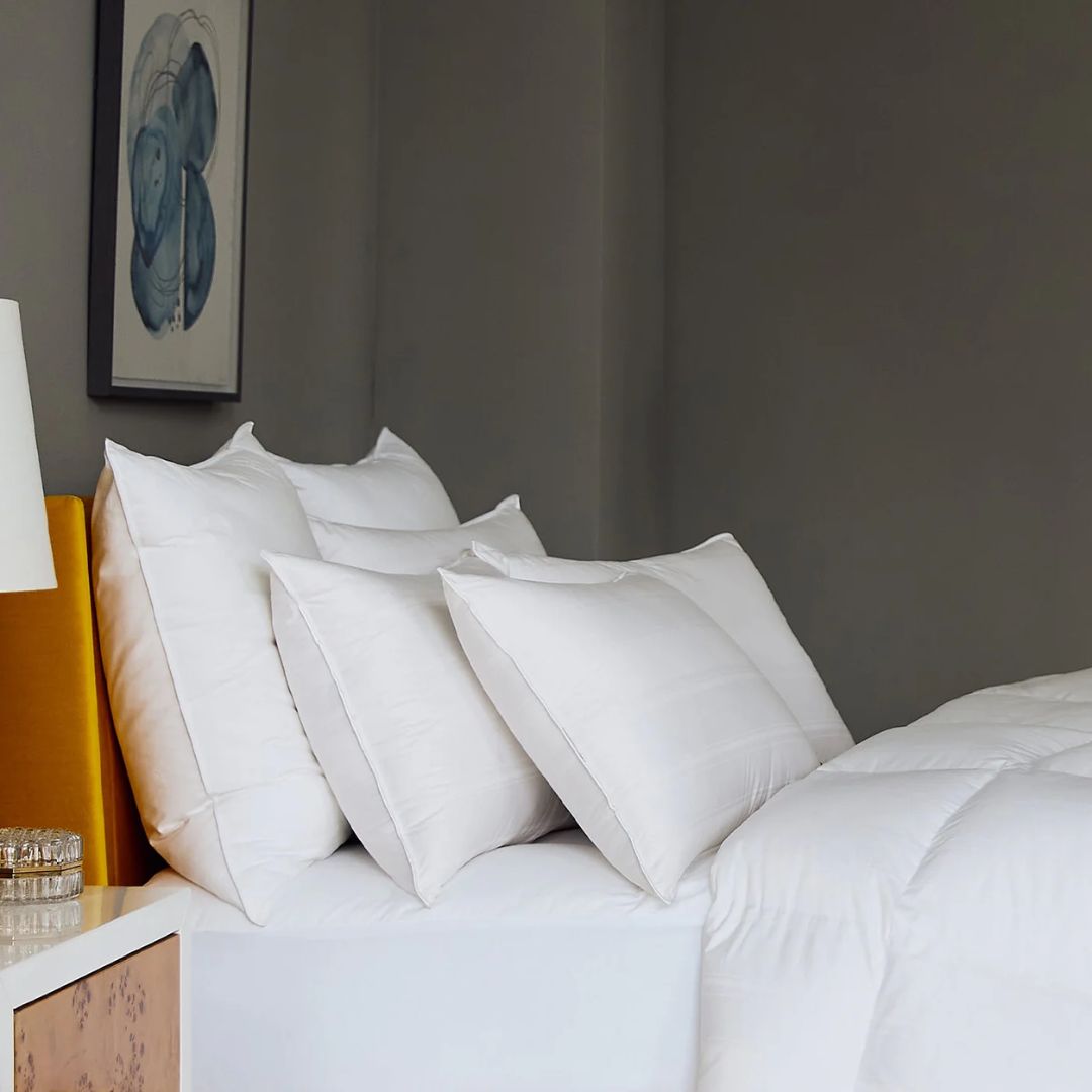 A neatly made bed with Scandia Home pillows and comforter, beside a nightstand with a lamp and wall art above.