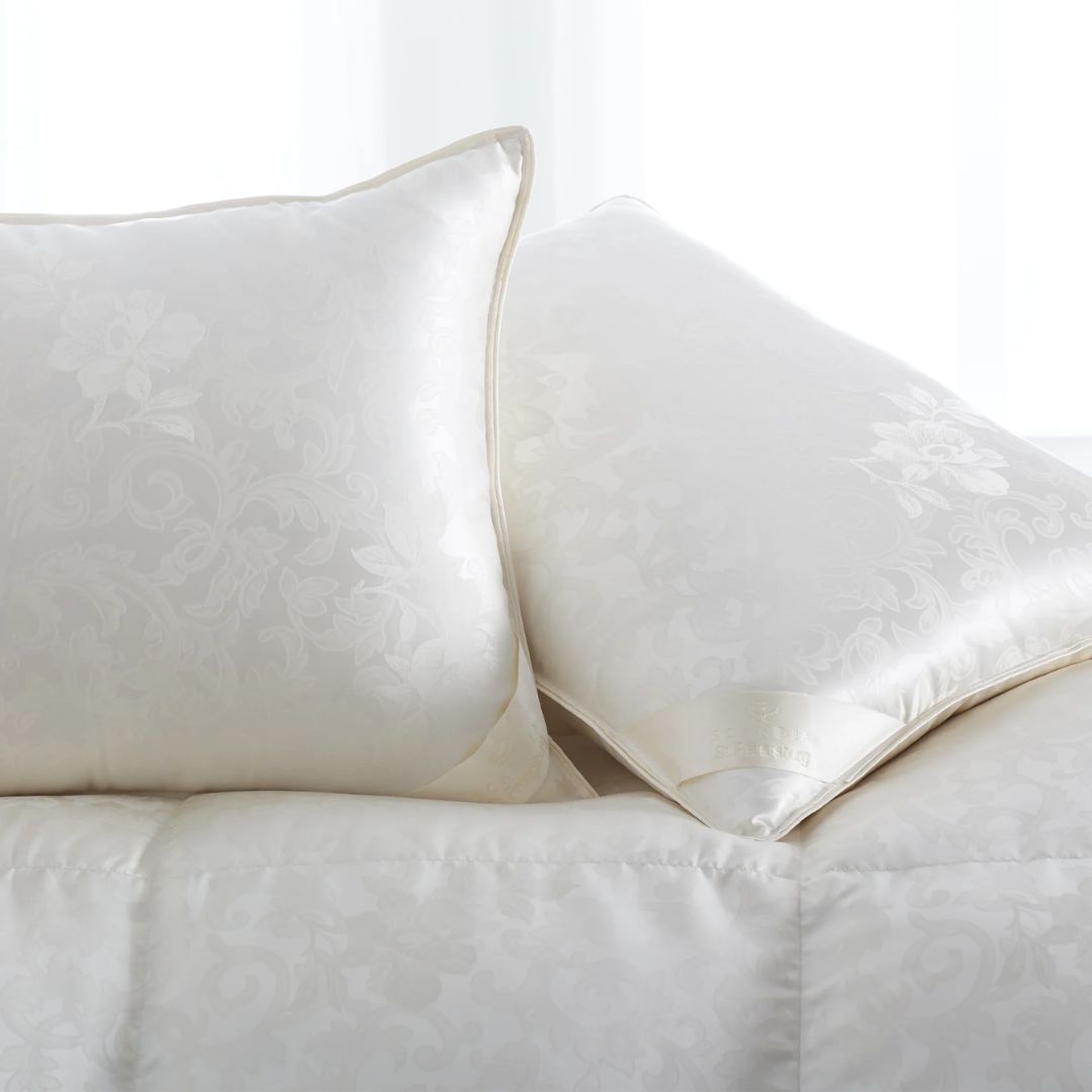 Two Scandia Home luxury down pillows with a subtle floral pattern rest on a matching white comforter.