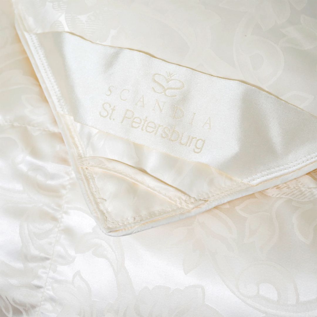Close-up of a cream-colored, silk damask fabric with a Scandia St. Petersburg luxury down comforter label sewn in the corner.