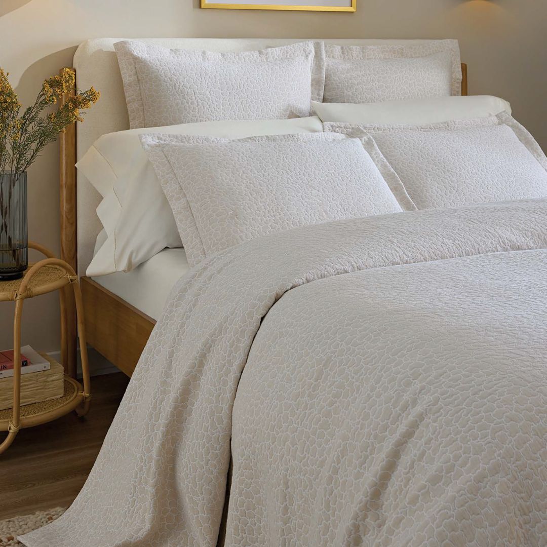 Neatly made bed with textured bedding in a bedroom setting.