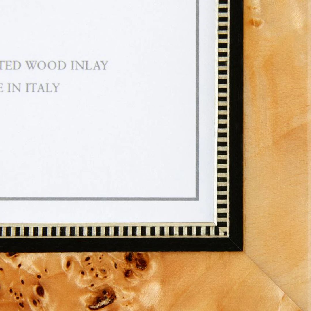 Close-up of a wood inlaid photo frame corner with a striped black and white border and partially visible text.