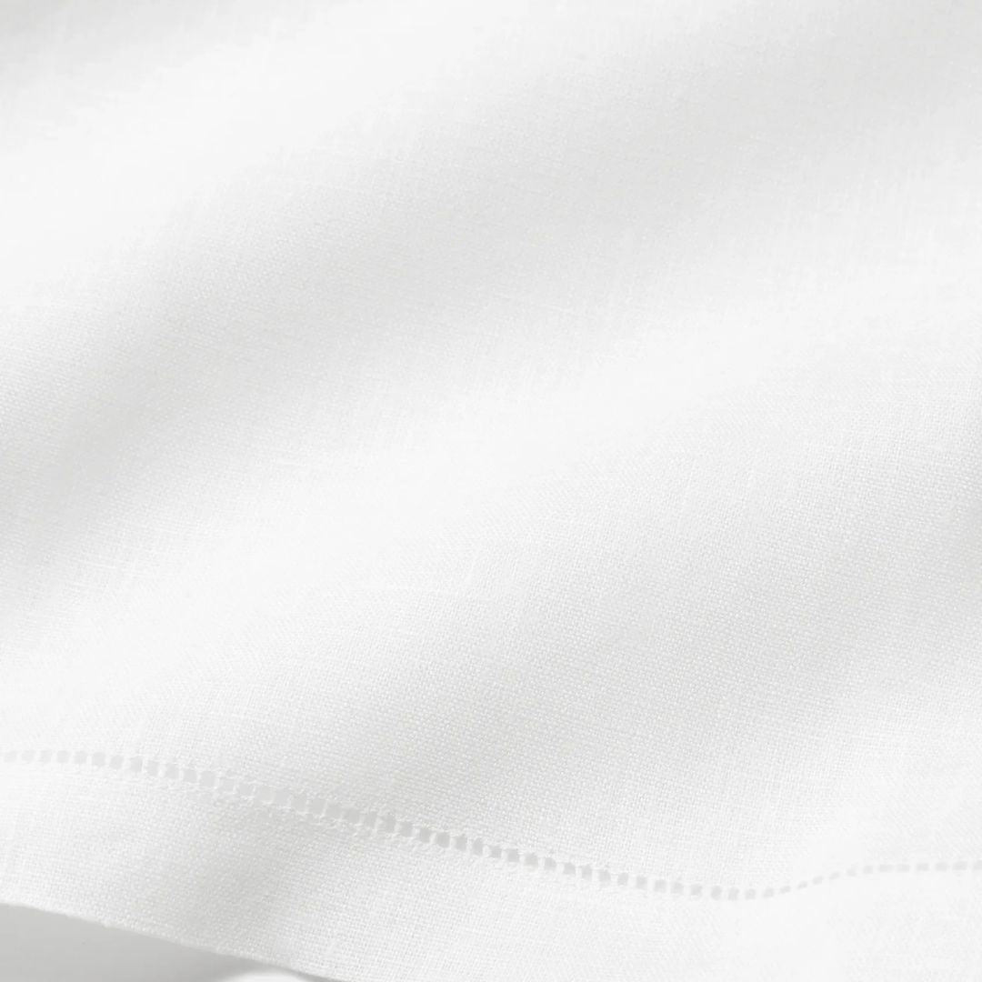 A close-up of monogrammed linen towels with subtle texture and a neatly stitched edge near the bottom of the image.