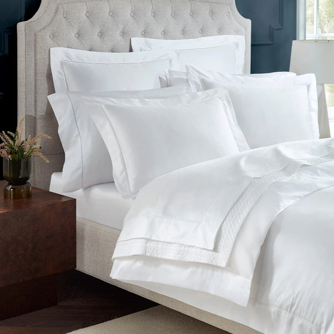 White bedding set on a bed with a wooden nightstand.