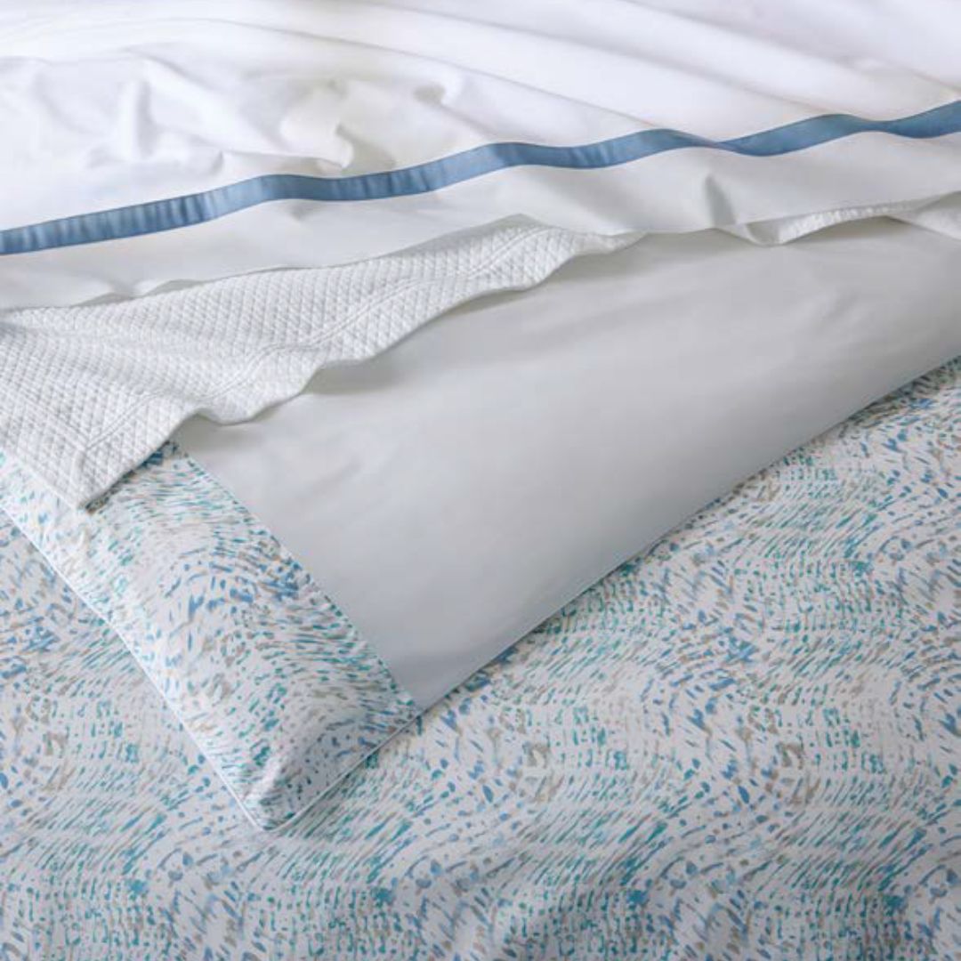 Close-up of a textured white pillow on a patterned bedspread