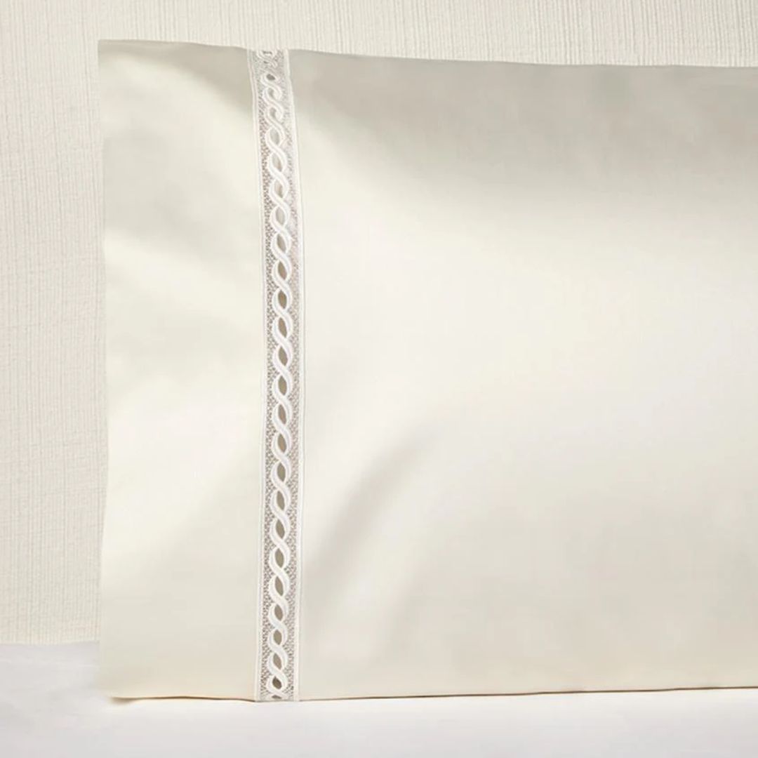 Cream-colored pillowcase with lace trim, crafted from Italian spun sateen, set against a light textured background.