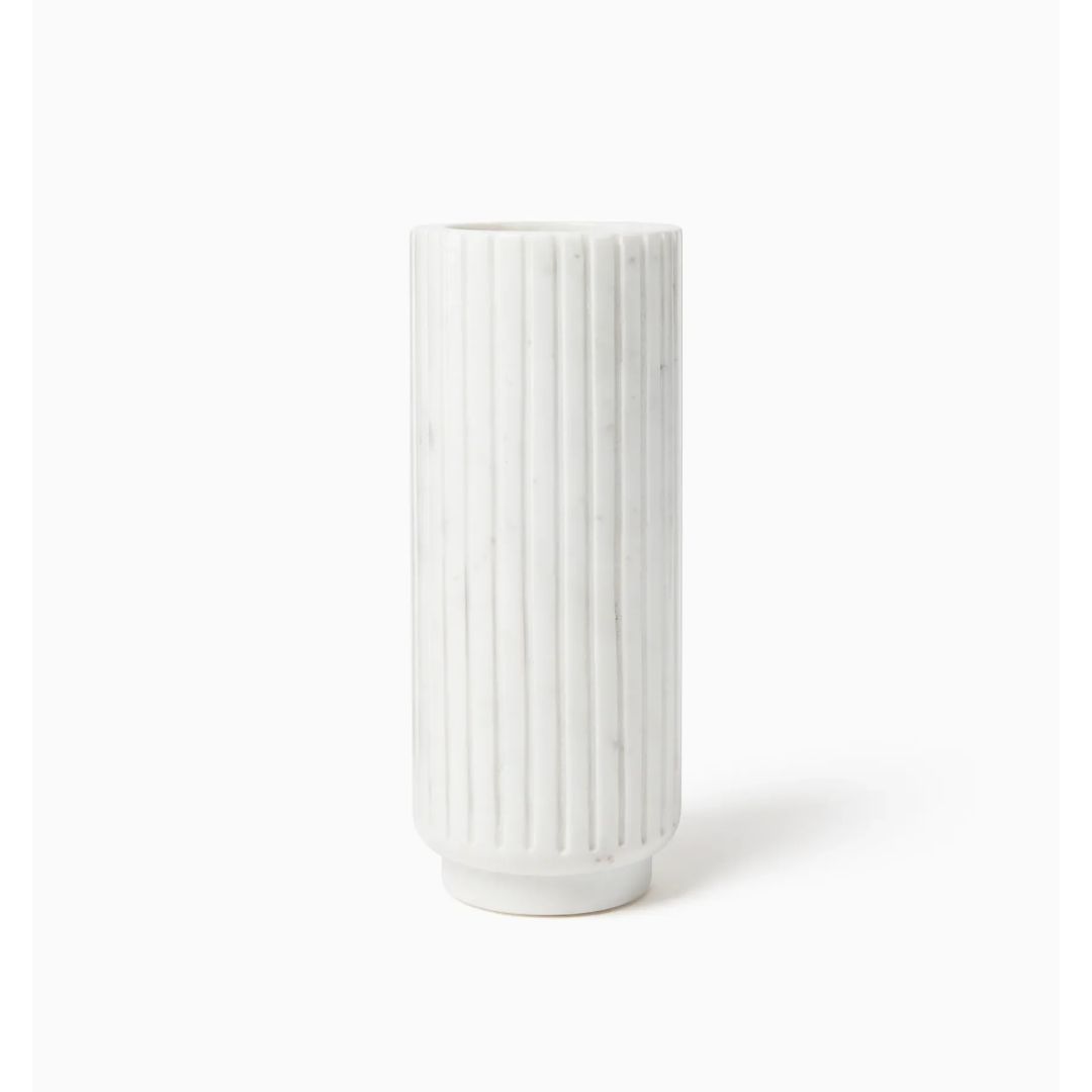 Tall, cylindrical white vase with vertical grooves, echoing architectural fluted marble, set against a plain background.