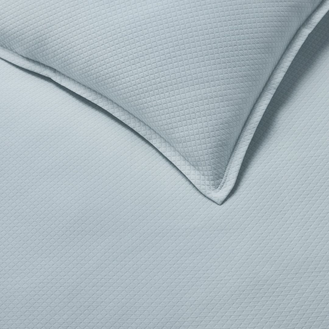 Close-up of a textured light blue sham and coverlet