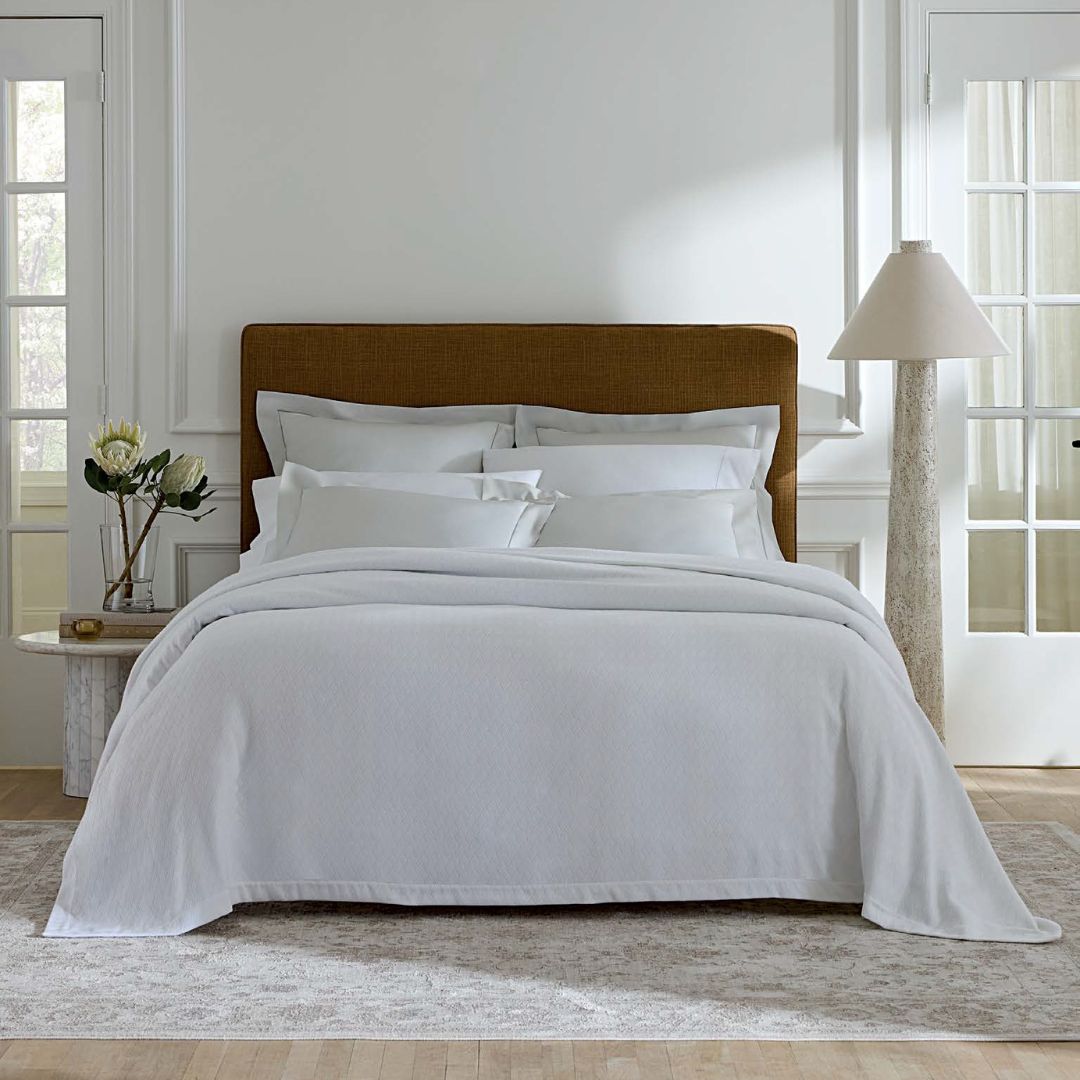 Bed with white bedding and wooden headboard in a bright bedroom