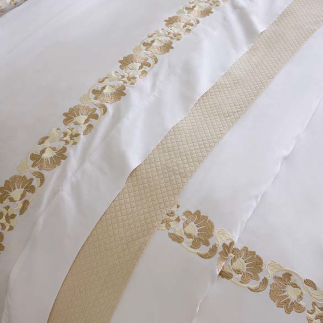 Close-up of white fabric with gold floral embroidery and textured stripe