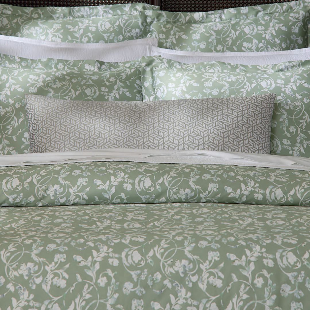 Close-up of sage green bedding with floral patterns and a chenille jacquard decorative pillow completing the look.