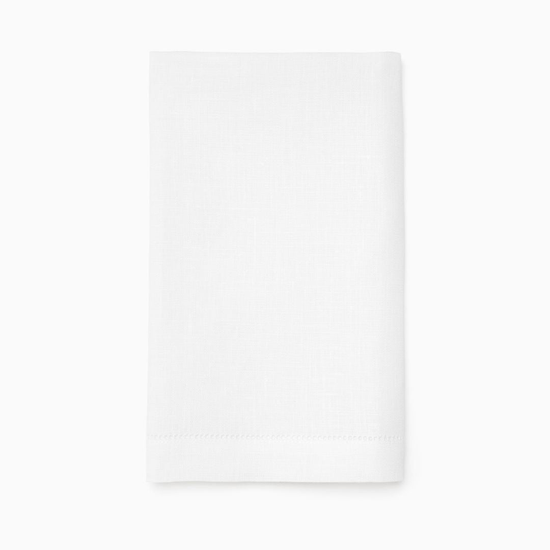 A neatly folded guest bath towel or linen tip towel rests on a plain white background, simple and elegant.
