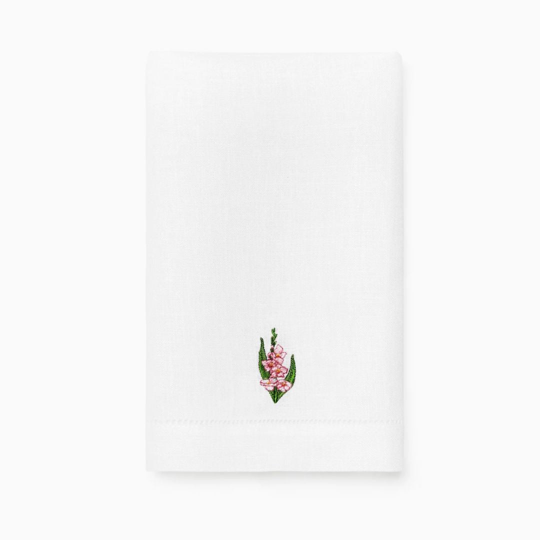 White linen guest towel with a small embroidered pink and green floral design near the bottom center.