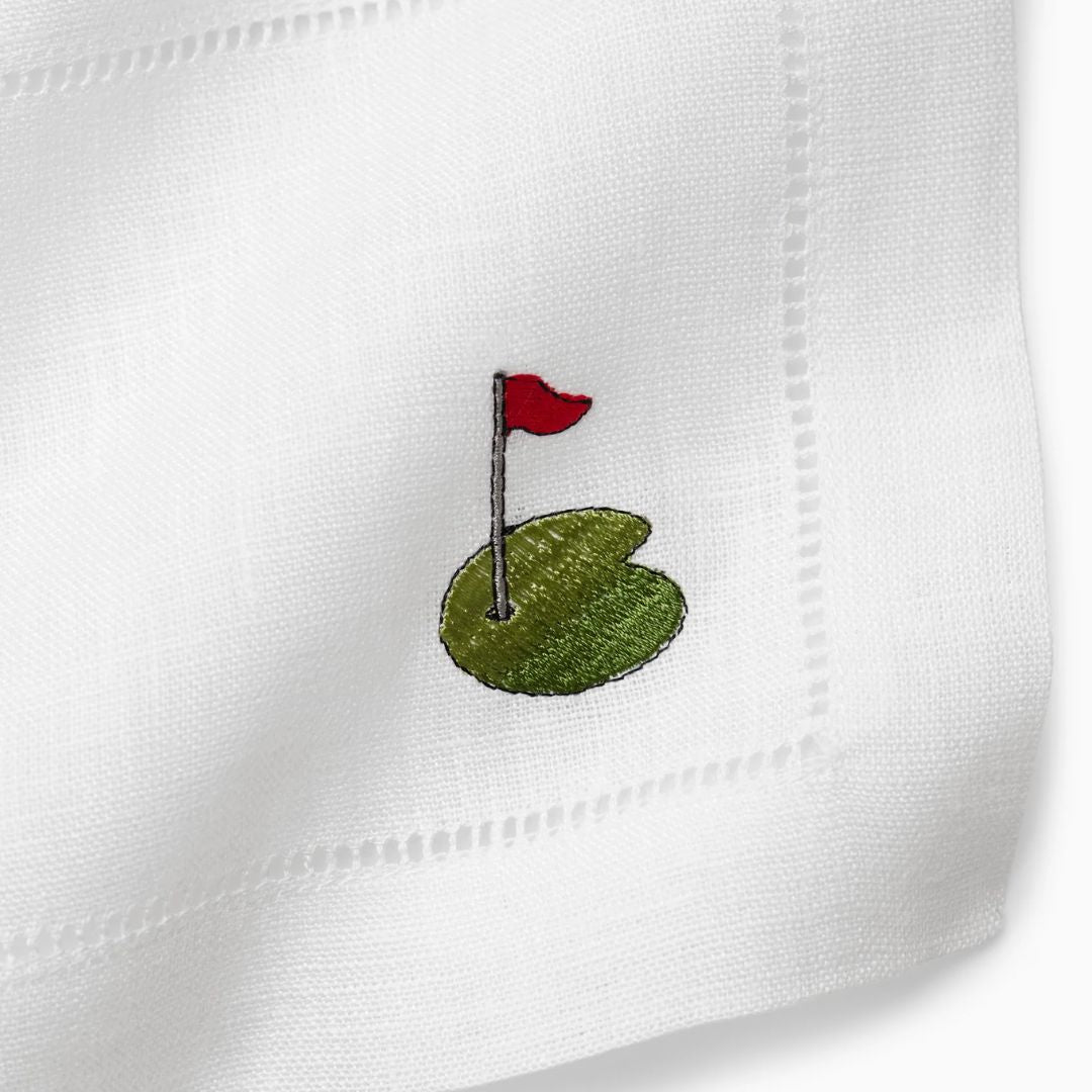 Embroidered golf flag and green on a white cocktail napkin