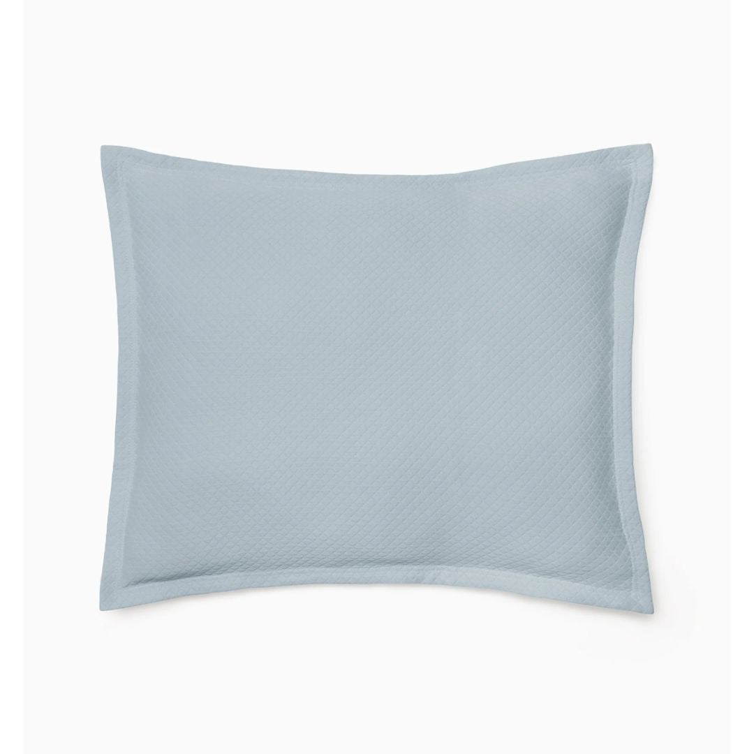 A light blue rectangular pillow in cotton matelassé pairs perfectly with the Rombo coverlet on a plain white background.