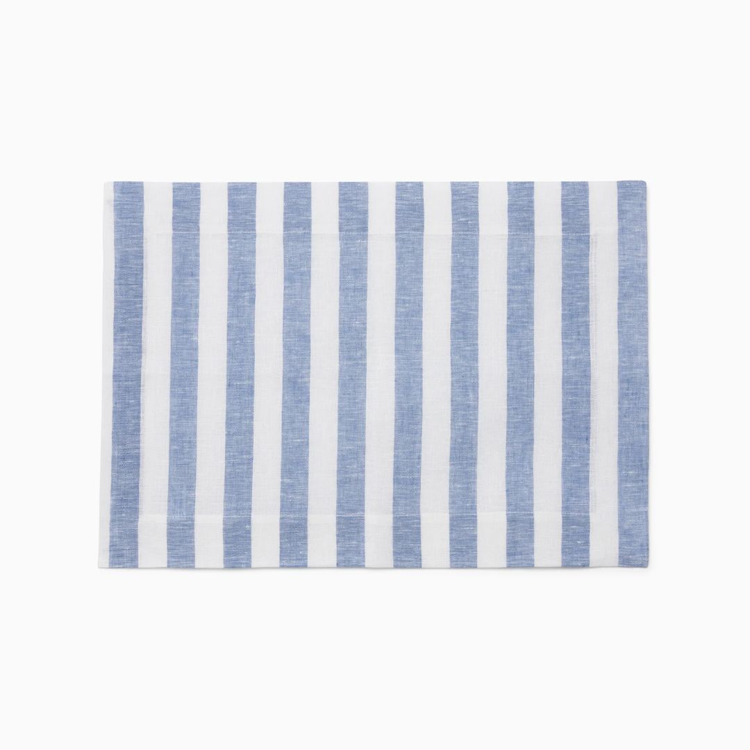 A rectangular placemat with vertical blue and white stripes, perfect for coastal table decor on a plain white background.