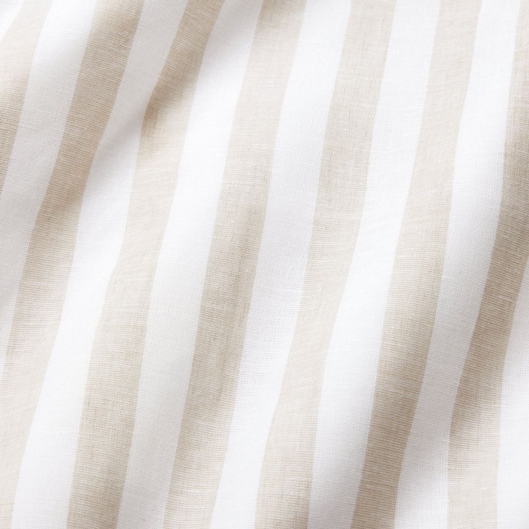 A round table set for breakfast with eggs, croissants, juice, fruit, and coastal table decor by a window.