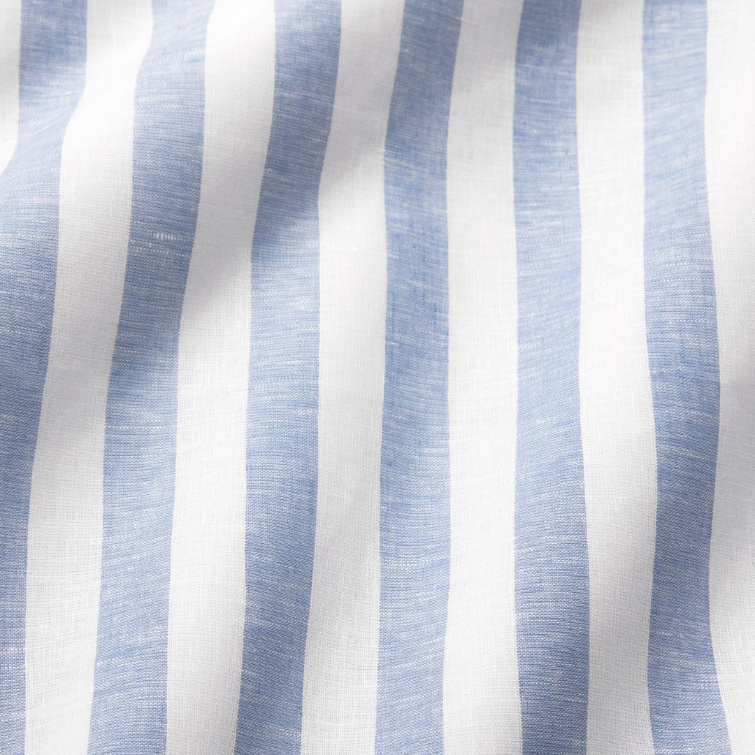 White linen table linens with vertical light blue stripes, slightly wrinkled—perfect for coastal table decor.