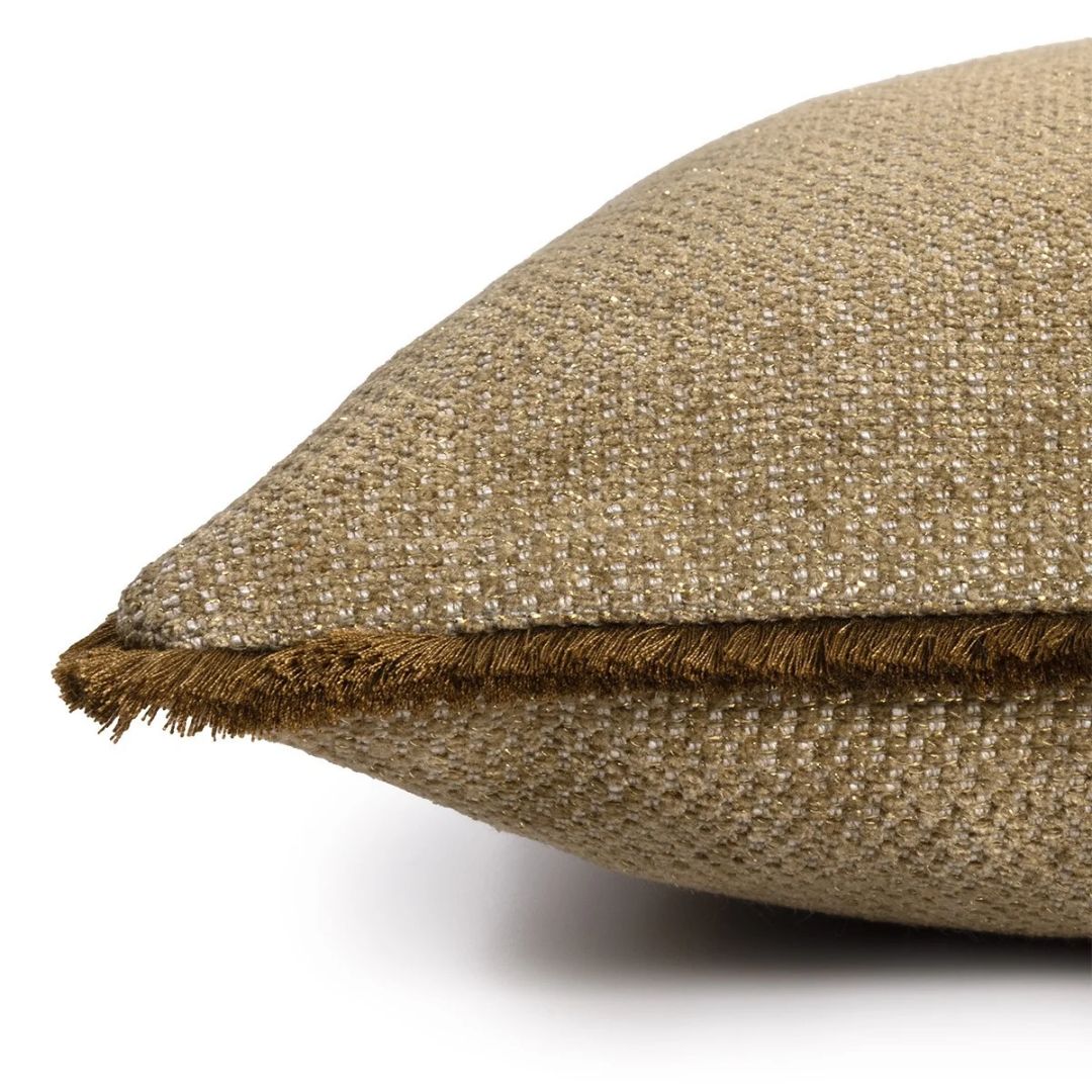 Close-up of a tan, woven decorative cushion with dark brown fringe trim.