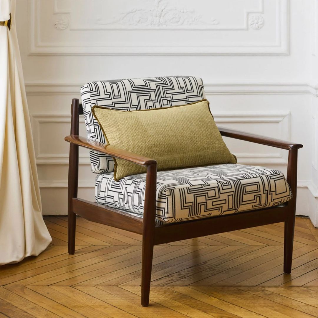 Armchair with a black-and-white geometric pattern and a rectangular olive green woven decorative cushion.