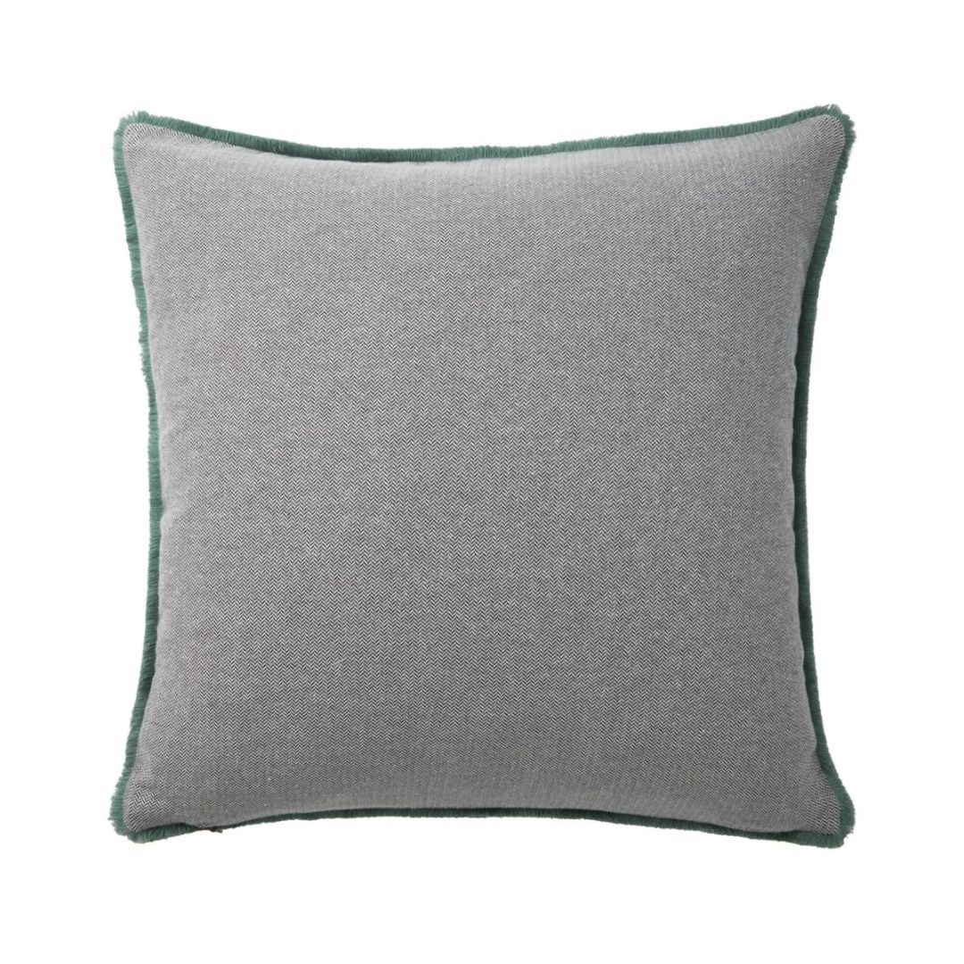 Square gray Yves Delorme throw pillow with a decorative feline design and a green fringed border.