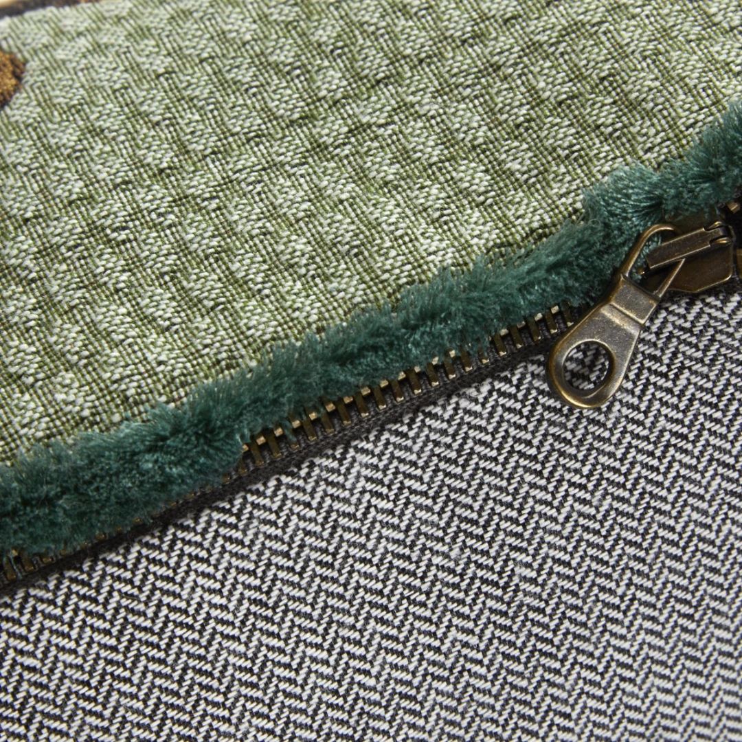 Close-up of a zipper joining green textured fabric and a grey herringbone cotton jacquard tapestry.
