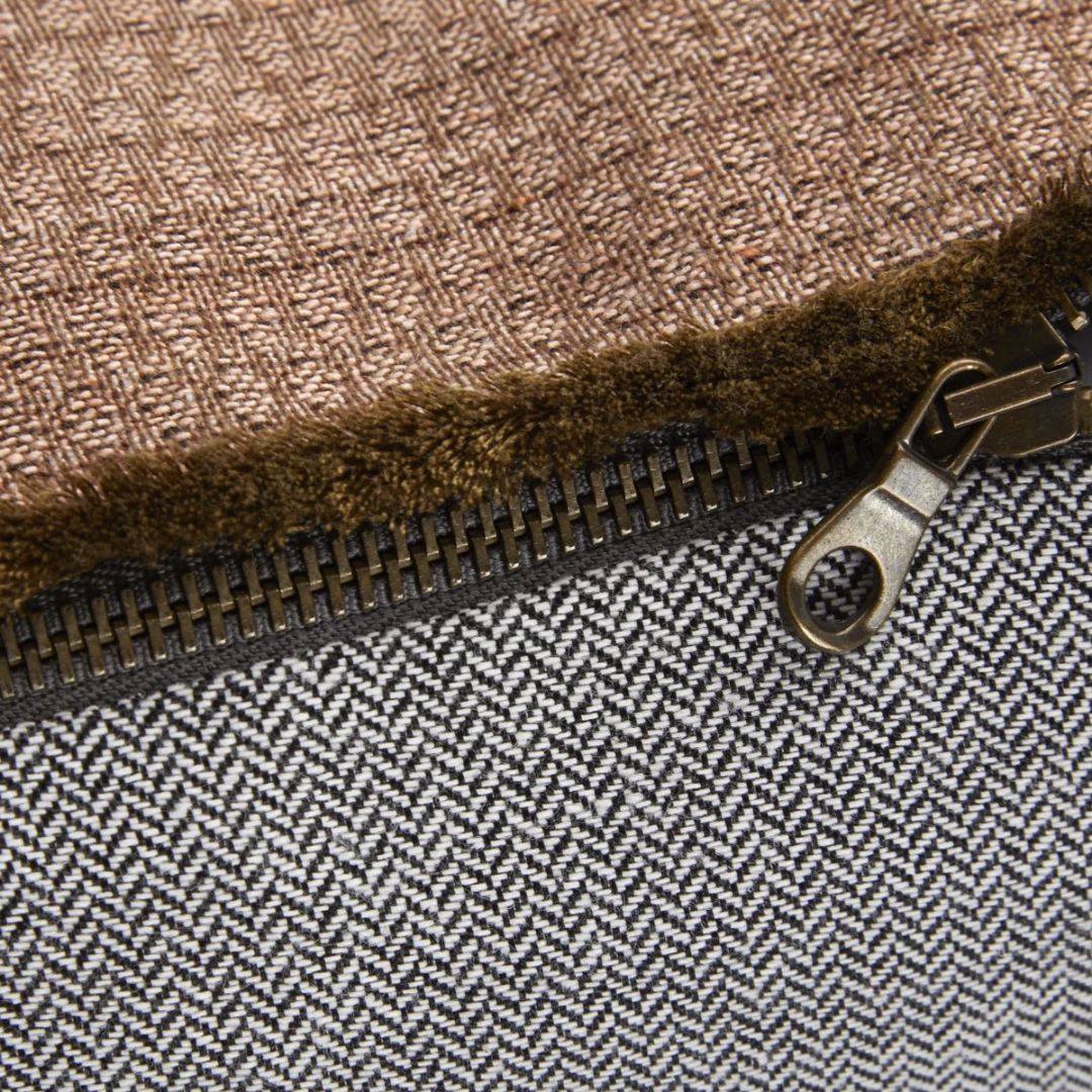 Close-up of a zipper on a cotton jacquard tapestry pillow featuring brown and black-and-white patterns.