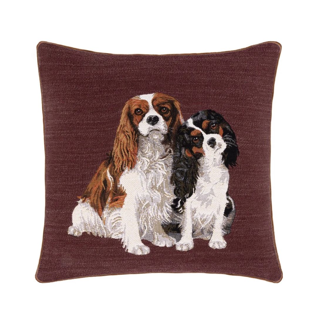 Square Yves Delorme decorative pillow featuring an embroidered portrait of a Blenheim and a tricolor Cavalier King Charles.