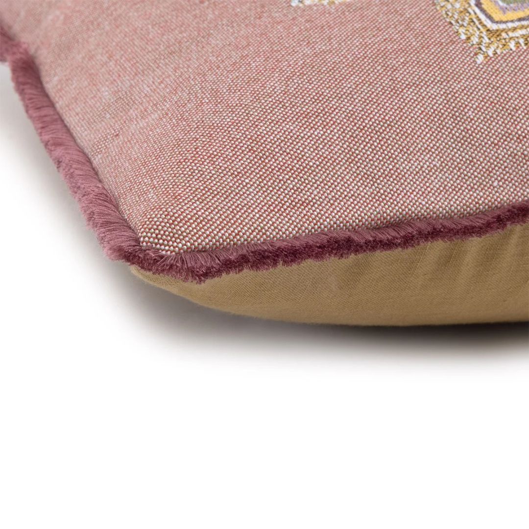 A close-up of a pink cotton jacquard tapestry cushion with a frayed edge and a solid tan underside.
