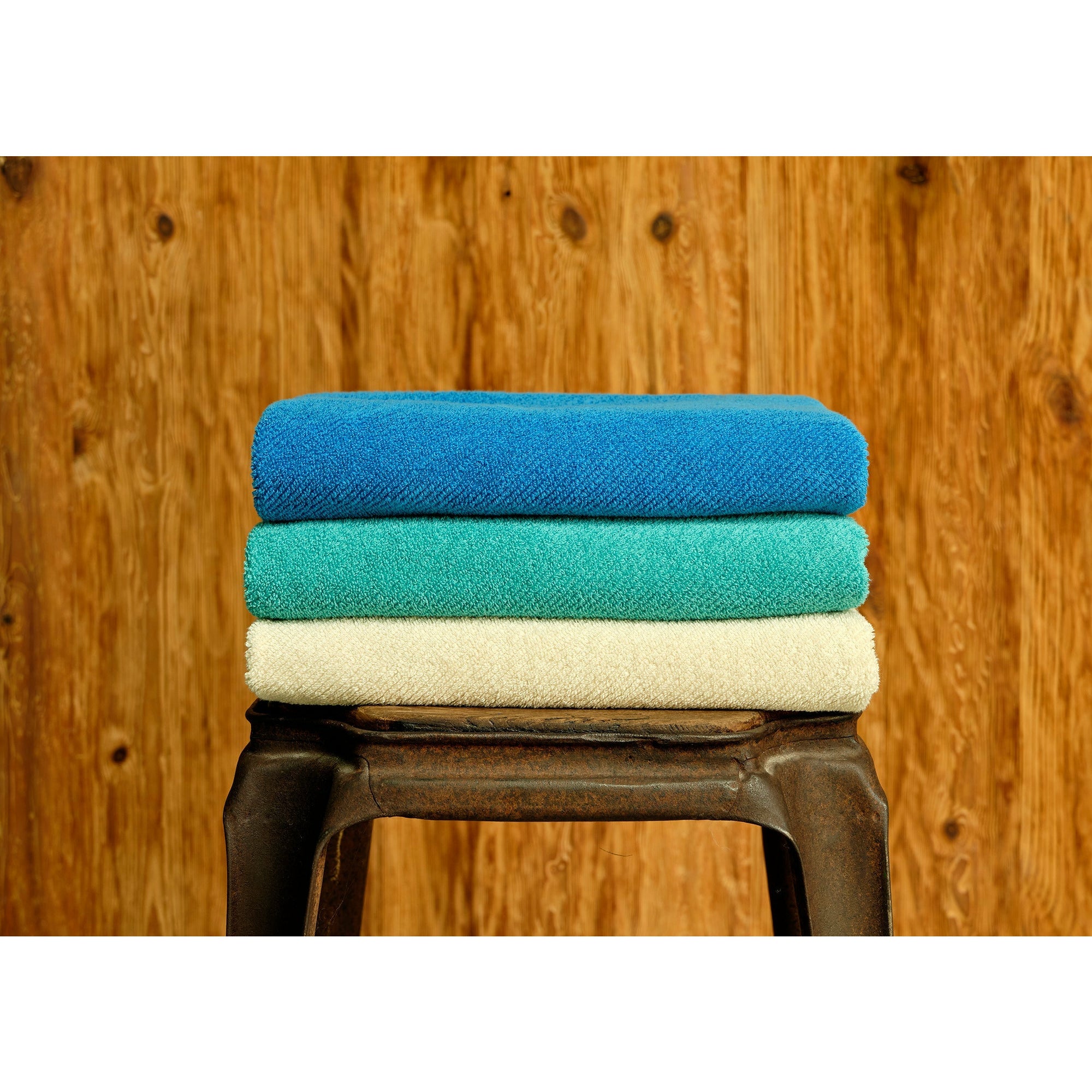 Stack of bath towels on wooden background. White and pink cotton