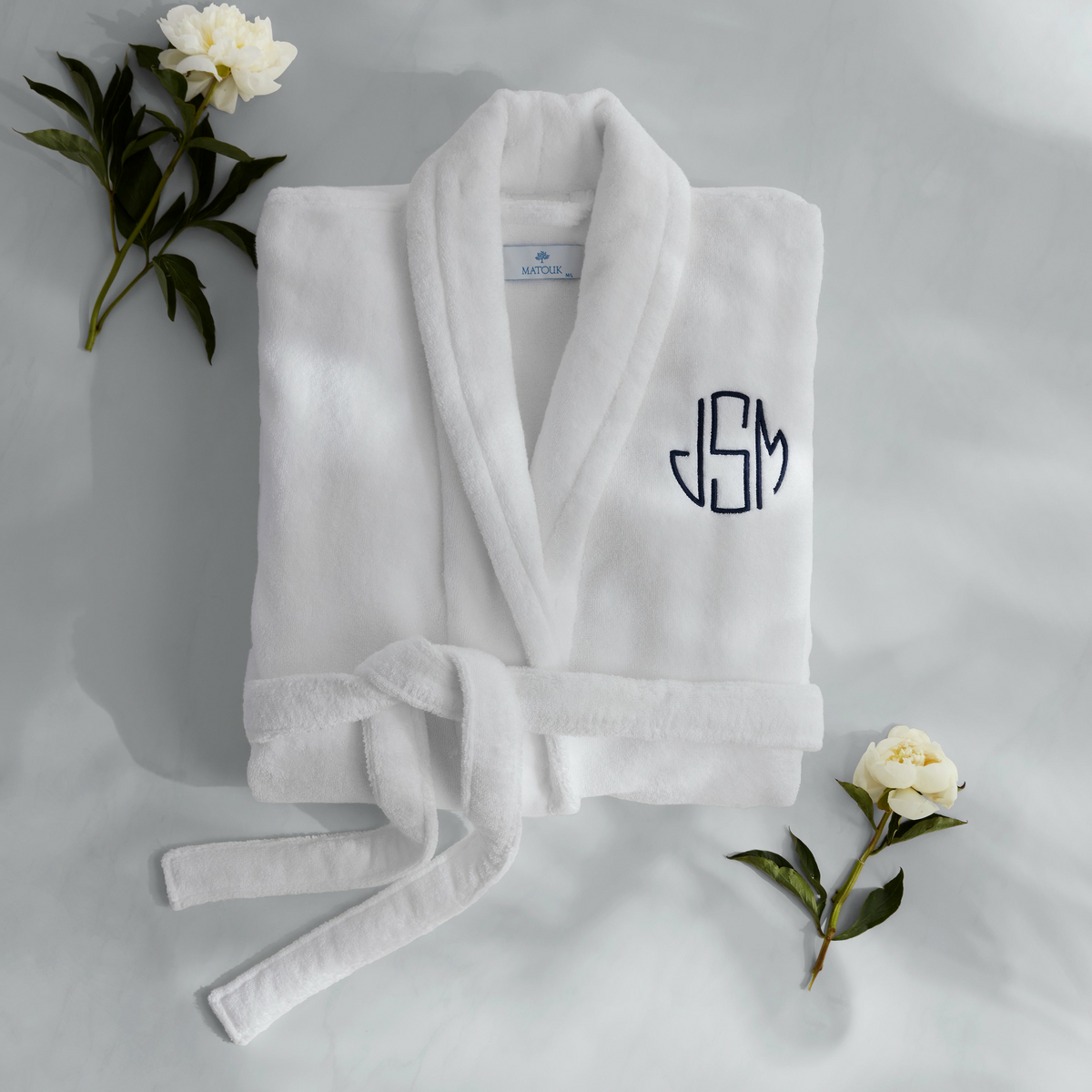 Matouk Milagro Bath Robe Lifestyle Folded with White Flowers Night