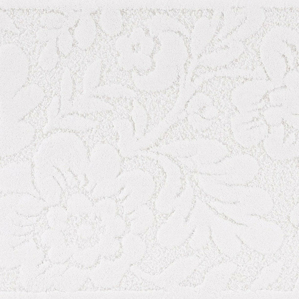 A white Abyss Habidecor Brighton bath rug with a subtle floral pattern.