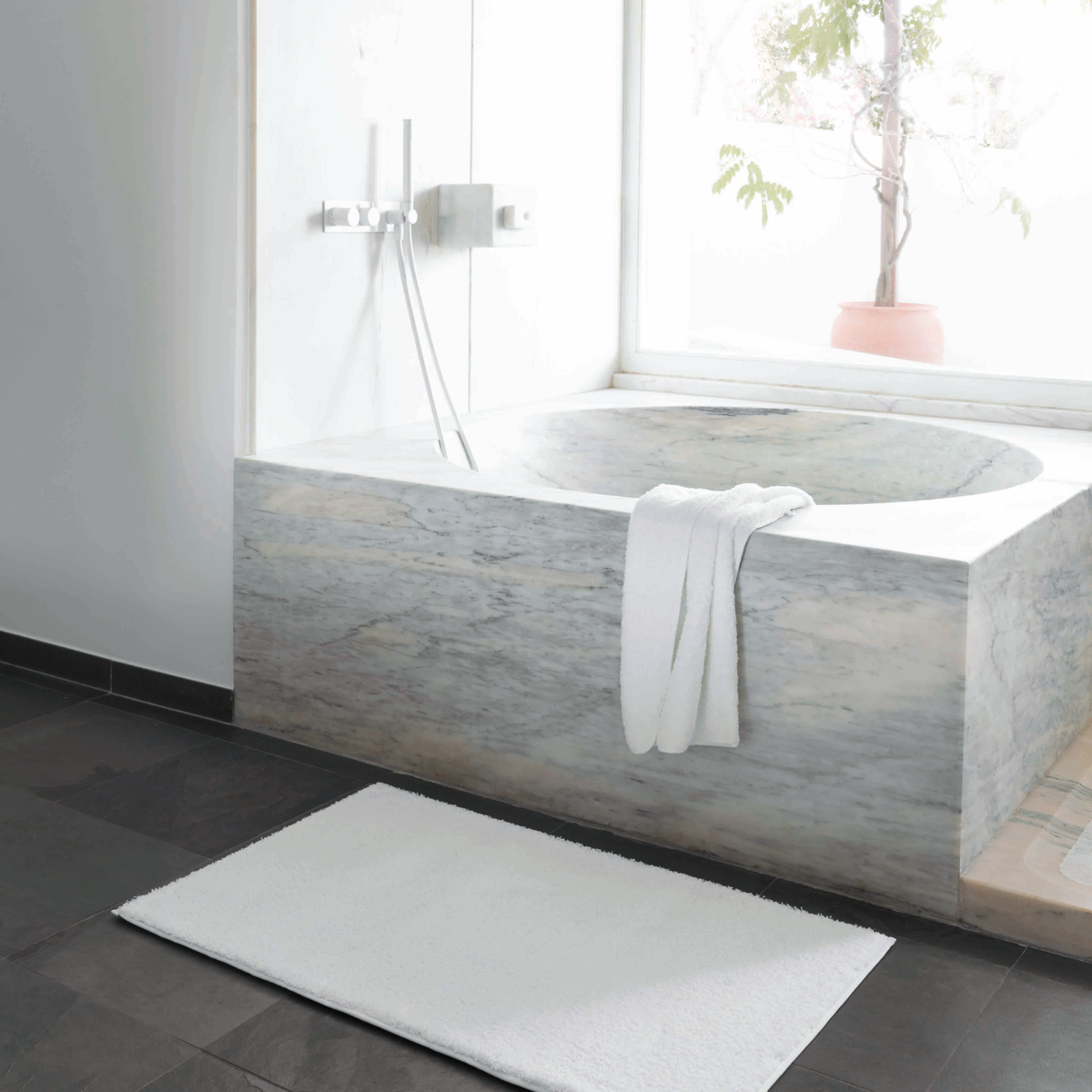 A White Graccioza Plain Egoist Bath Rug on the Floor Beside a Tub 