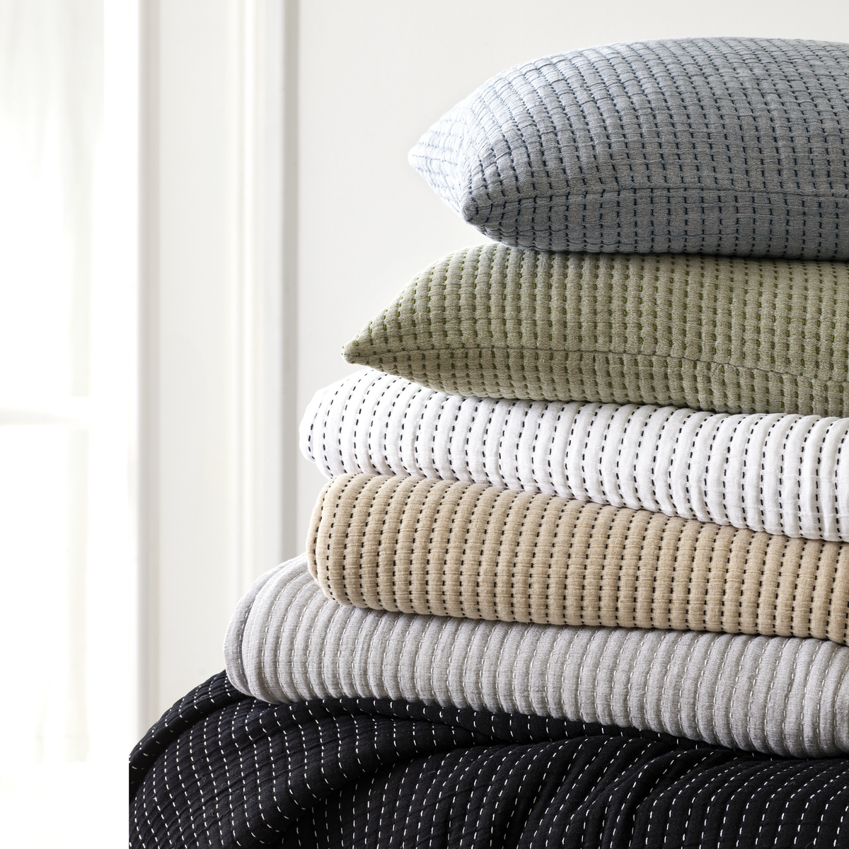 Stack of Differently Colored Pine Cone Hill Pick Stitch Matelassé Coverlet &amp; Shams